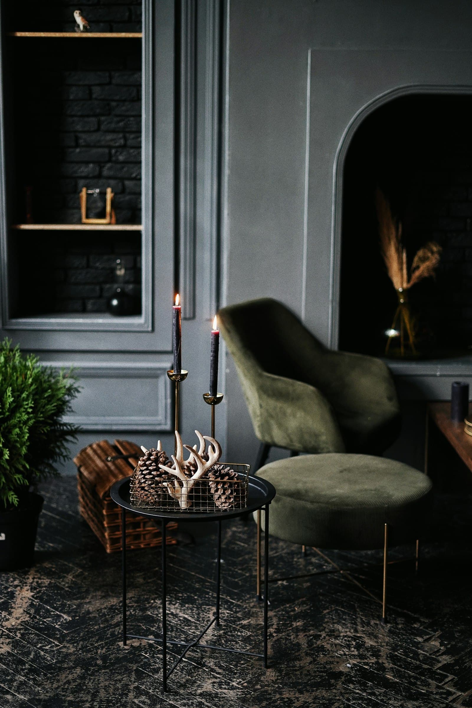 Séjour sombre et feutré, fauteuil velours, bougies et niche en arche.