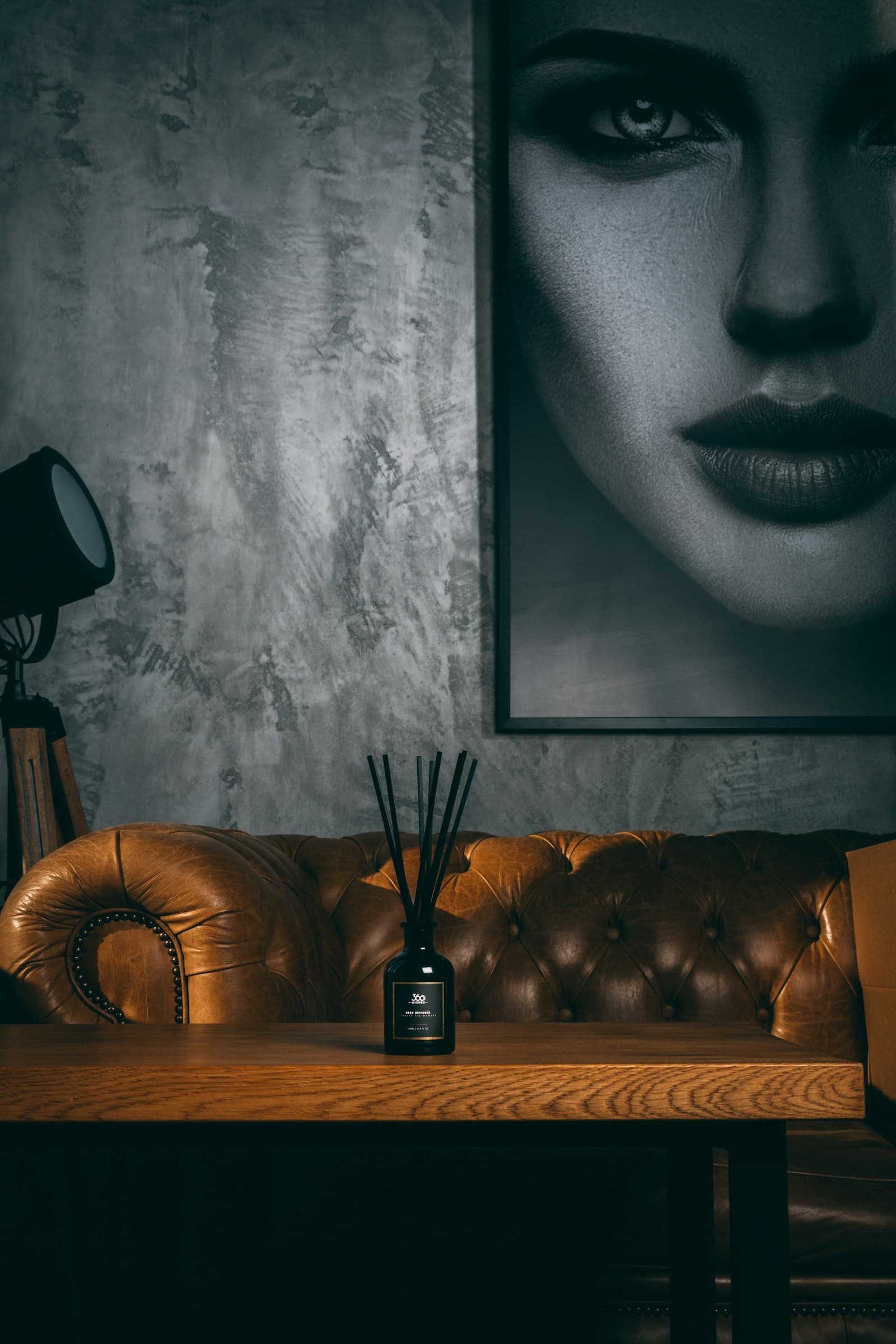Salon chaleureux d’une résidence privée : canapé en cuir fauve, mur texturé et lumière tamisée.